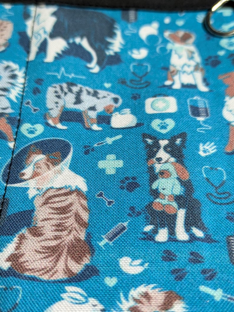 May include: Blue fabric with a repeating pattern of dogs, hearts, bones, and medical symbols. The dogs are in various poses and breeds, including a border collie, a husky, and a terrier.