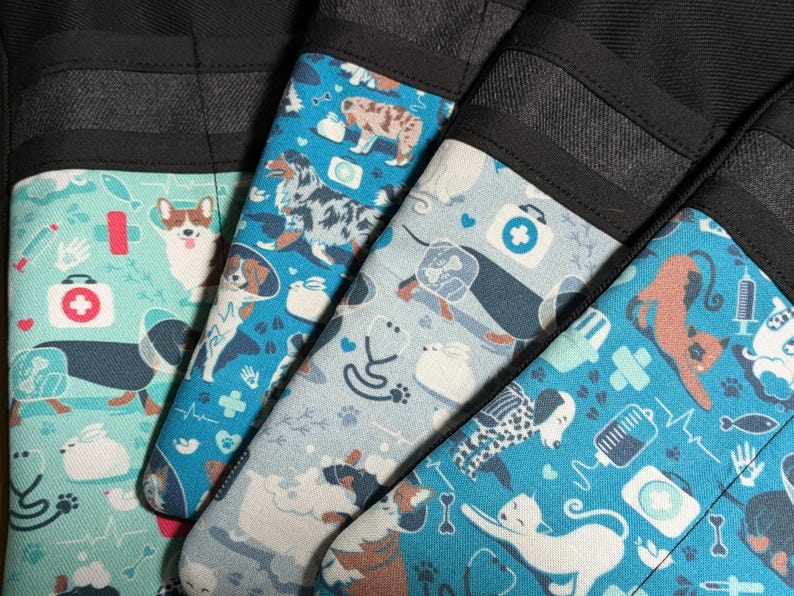 May include: Four black fabric pockets with blue and white patterned fabric inserts. The patterns feature various animals, including dogs, cats, and a rabbit. The patterns also include medical symbols, such as a stethoscope, a bandage, and a first aid kit.