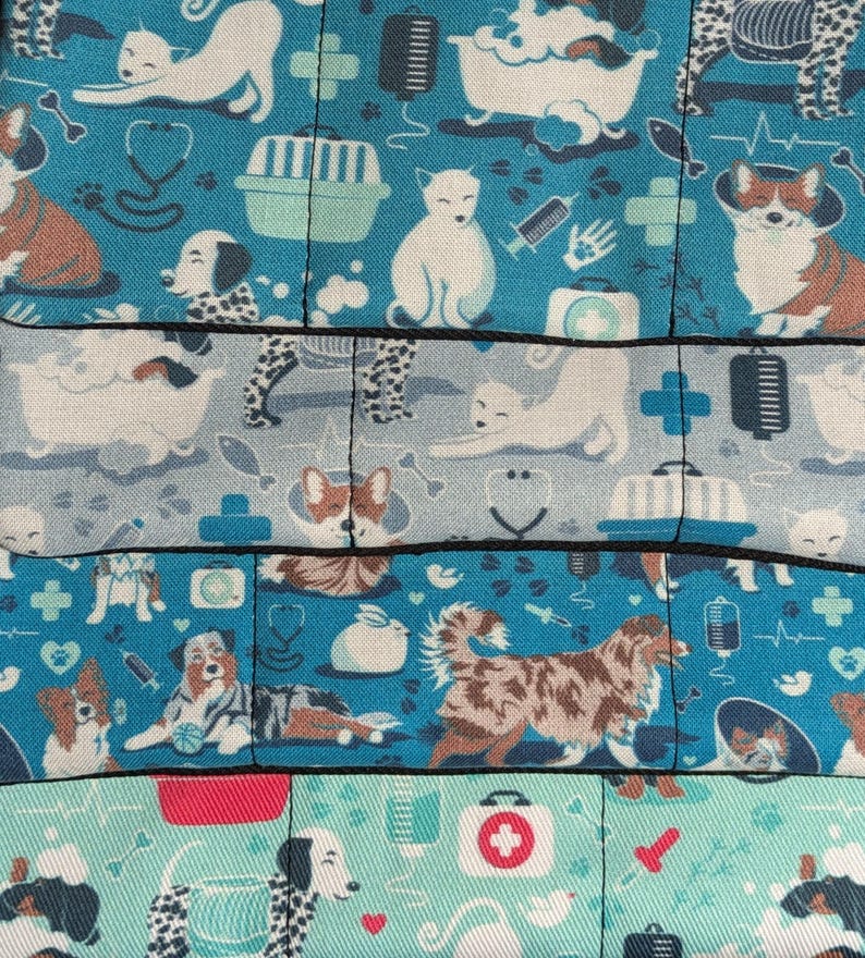 May include: A blue and white fabric with a repeating pattern of dogs, cats, and veterinary-themed symbols. The fabric features a variety of breeds, including a corgi, a dalmatian, a terrier, and a cat. The symbols include a stethoscope, a first aid kit, a bone, and a paw print.