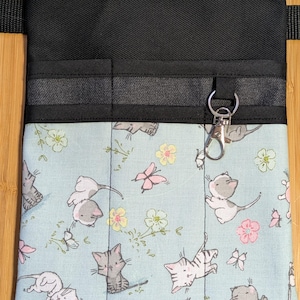 May include: A black utility belt with a light blue fabric pouch featuring a repeating pattern of white cats and butterflies. The pouch has multiple pockets and a silver key chain.