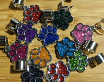 May include: A collection of 10 silver charm bracelets with paw print charms. The charms are filled with glitter in various colors, including red, green, blue, pink, purple, orange, and black.