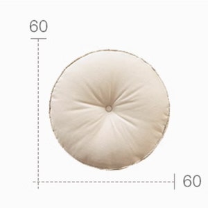 May include: Three round floor cushions, each measuring 60 cm in diameter. The cushions are made of a soft, textured fabric. One cushion is grey, one is beige, and one is green.