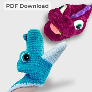 May include: Two handmade crochet monster toys. One is turquoise with a white and light blue horn, and the other is a deep magenta color. Both have large, expressive eyes and are made of soft, plush yarn. The text "PDF Download" is in the top left corner.