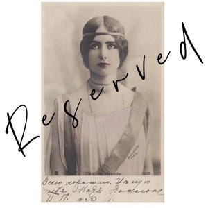 Pode incluir: Um cartão postal vintage em tom sépia com um retrato de Cléo de Mérode usando uma faixa na cabeça e uma peça de roupa clara. A imagem inclui o texto 'Cléo de Mérode' e 'Reutlinger Paris' junto com escrita cirílica manuscrita na parte inferior.