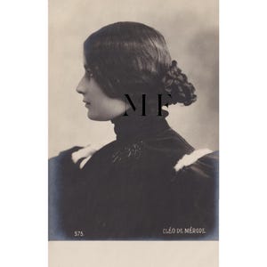 Pode incluir: Fotografia vintage a preto e branco de uma mulher em perfil. Ela usa uma roupa escura de gola alta com detalhes brancos. O cabelo está preso num coque. O texto "MF" é visível, juntamente com "CLÉO DE MÉRODE" e o número "575."