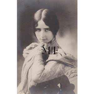 Pode incluir: Fotografia vintage em preto e branco de uma mulher com cabelo escuro, vestindo uma roupa drapeada. A imagem tem foco suave e inclui as iniciais "NF" e uma assinatura manuscrita.