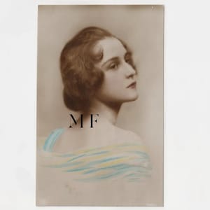 May include: Sepia-toned portrait of a woman with short, wavy brown hair, looking to the side. She wears a light blue and yellow scarf or shawl. The initials "MF" are printed in black on the image.