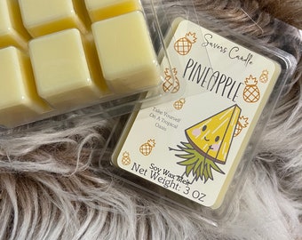 May include: A clear plastic container with six wax melts shaped like cubes. The wax melts are a pale yellow color. The container is labeled "Savers Candle PINEAPPLE" with a cartoon pineapple illustration. The label also says "Soy Wax Melt" and "Net Weight: 3 OZ".