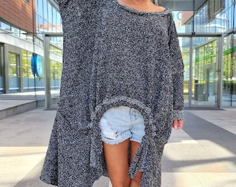 May include: A black and white speckled sweater with a high-low hemline. The sweater is worn with denim shorts and black sneakers.