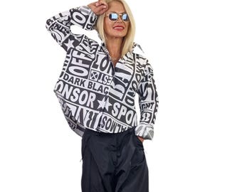 May include: A long-sleeved button-down shirt featuring a bold black and white graphic print with various words including "OFF", "DARK", "BLACK", "SPORT", and "ALMOST" scattered across the fabric, paired with solid black trousers.