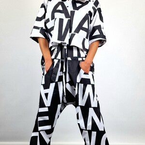 May include: A black and white patterned shirt and trousers set. The shirt is a cropped style with a button-up front. The trousers are loose-fitting with a wide leg. The model is wearing a black hat and sunglasses.