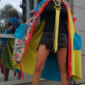 Może przedstawiać: Kobieta w kolorowym kimonie z wieloma wzorami, z ż&oacute;łtym naszyjnikiem z frędzlami, czarną koszulą na ramiączkach, podartymi dżinsowymi szortami i czarno-białymi sznurowanymi butami.