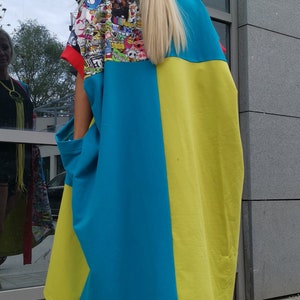 Może przedstawiać: Kobieta w niebiesko-ż&oacute;łtej sukience z kolorowym nadrukiem graficznym na plecach. Ma na sobie czarno-białe szachownice.