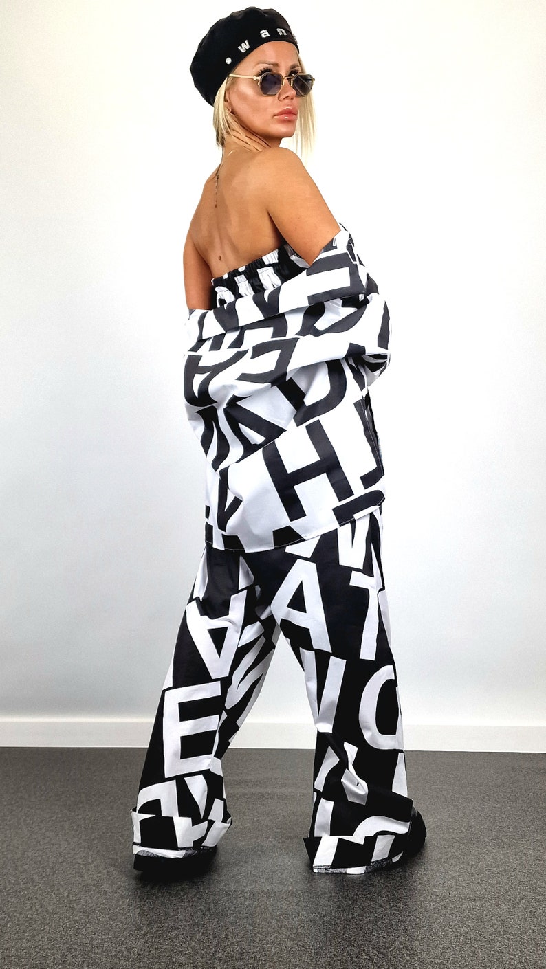 May include: A black and white patterned trouser suit with a black beret. The beret has the word "WANT" written on it in white letters.