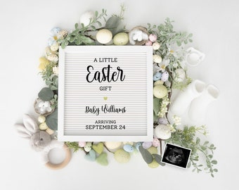 May include: A white letter board with the text "A Little Easter Gift Baby Williams Arriving September 24". The board is surrounded by pastel colored eggs, green leaves, and a white bunny rabbit toy.