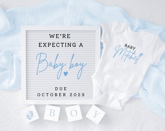 May include: A white letter board with the text "We're expecting a Baby boy Due October 2023". A white onesie with the text "Baby Mitchell" in blue script.  Four white blocks with the letters "B O Y" and a blue footprint.