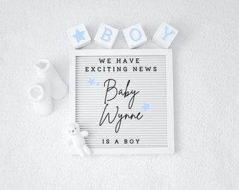 May include: A white letter board with the text "We have exciting news. Baby Wynne is a boy."  There are blue stars and the letters "BOY" spelled out with wooden blocks.