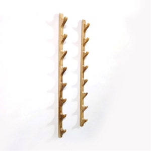 May include: Two wooden wall mounted coat racks with multiple hooks. The racks are made of natural wood and have a rustic look.