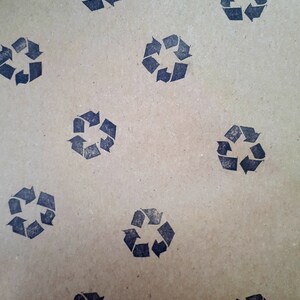 May include: A brown paper sheet with a repeating pattern of black recycle symbols. The symbols are made up of arrows forming a circle.