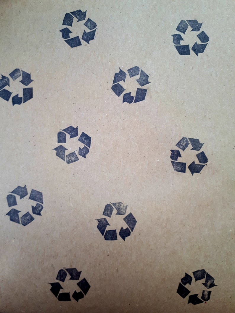 May include: A brown paper sheet with a repeating pattern of black recycle symbols. The symbols are made up of arrows forming a circle.