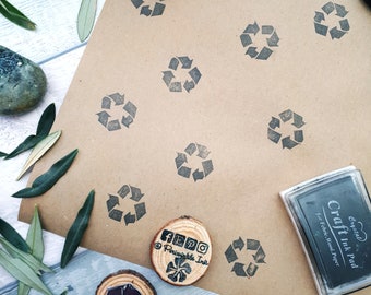 Könnte beinhalten: Ein braunes Papierblatt mit mehreren schwarzen Recycling-Symbolen, die darauf gestempelt sind. Es gibt einen Stempel aus Holz mit dem Text "Periwinkle Ink" und ein schwarzes Stempelkissen mit dem Text "Crystal Craft Ink Pad for Fabric, Wood, Paper".