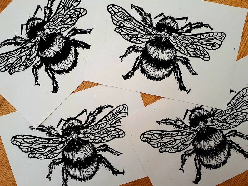 Puede incluir: Cuatro tarjetas rectangulares blancas con una ilustraci&oacute;n en tinta negra de un abejorro. El insecto tiene un cuerpo peludo con rayas distintivas y alas decoradas con intrincados patrones geom&eacute;tricos repetitivos y l&iacute;neas finas.