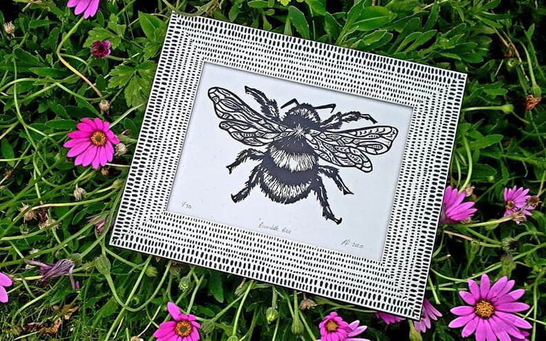 Puede incluir: Un grabado en lin&oacute;leo en blanco y negro de un abejorro dentro de un marco rectangular con un patr&oacute;n de rayas. La impresi&oacute;n presenta el texto escrito a mano "Bumble bee" en la parte inferior, junto al n&uacute;mero "1/50" y las iniciales "AF 2020".