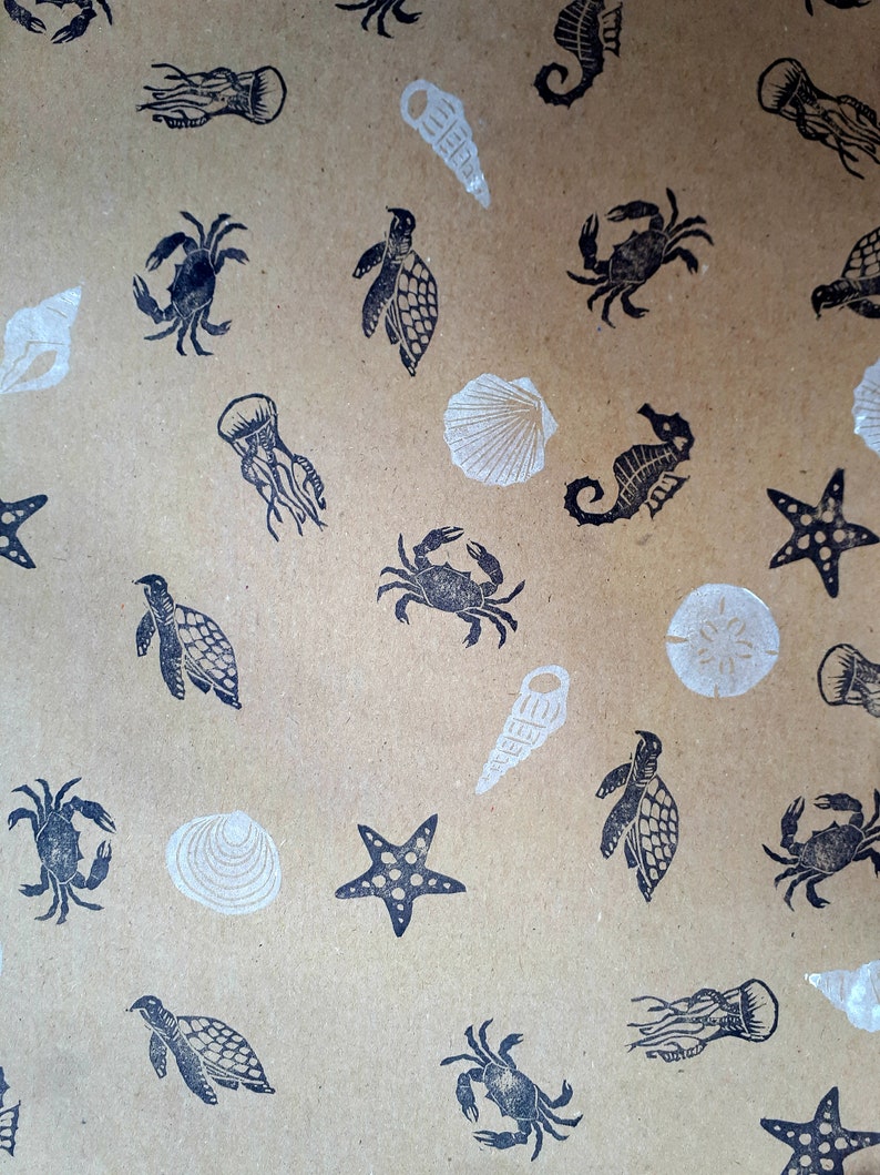 May include: A brown paper gift wrap with a repeating pattern of black sea creatures and white seashells. The pattern includes starfish, seahorses, crabs, turtles, and jellyfish.