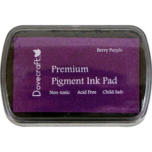 May include: A purple Dovecraft Premium Pigment Ink Pad in a clear plastic case. The ink pad is labeled "Berry Purple" and is described as "Non-toxic, Acid Free, Child Safe".