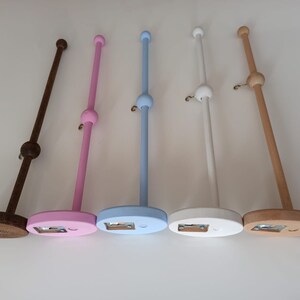 May include: Five wooden dowel rods with a ball on top and a base. The dowels are painted in different colors: brown, pink, light blue, white, and natural wood.