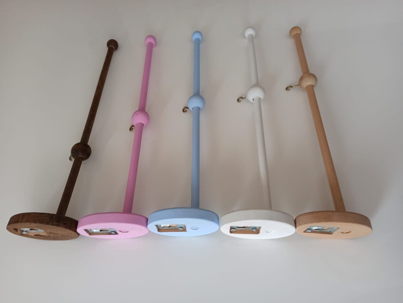 May include: Five wooden dowel rods with a ball on top and a base. The dowels are painted in different colors: brown, pink, light blue, white, and natural wood.