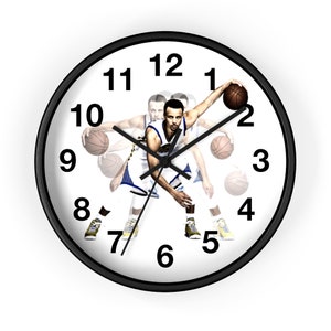 May include: A black and white wall clock with a basketball player in the center. The clock face has black numbers and hands. The player is wearing a blue and white jersey and is holding a basketball.