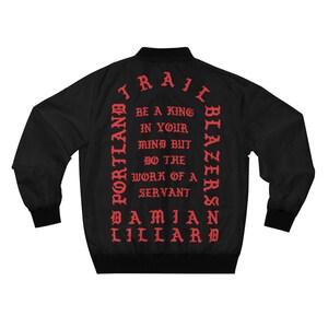 May include: Black bomber jacket with red text on the back. The text reads "TRAIT PORTLAND BLAZERS NB DAMIAN LILLARD" and "BE A KING IN YOUR MIND BUT DO THE WORK OF A SERVANT".