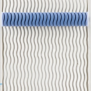 Puede incluir: Primer plano de un rodillo texturizado azul con un patrón ondulado. El rodillo está sobre una superficie blanca con un patrón ondulado similar.