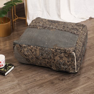 May include: A gray and brown patterned square floor cushion with a white trim. The cushion is made from recycled materials and is perfect for adding a touch of bohemian style to your home.