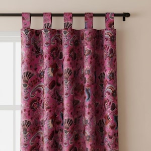 May include: Magenta curtains with a paisley pattern, hanging from a black rod. The paisley design incorporates burgundy, blue, and cream hues. The curtains are designed with tab tops for easy hanging.