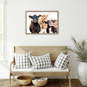 May include: A framed watercolor painting of four cows with brown and white markings. The cows are looking directly at the viewer with their tongues sticking out. The painting is set against a white background.