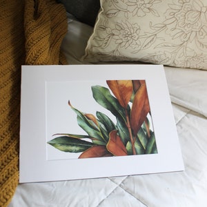 May include: A framed watercolor painting of a cluster of green and orange leaves. The leaves are arranged in a loose, organic pattern, and the colors are vibrant and realistic.