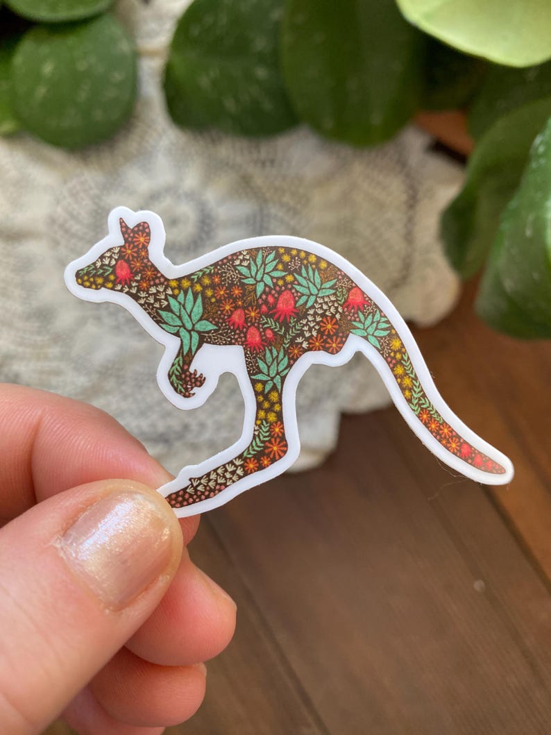 May include: A sticker of a kangaroo with a floral pattern. The kangaroo is brown with red, orange, yellow, and green flowers. The sticker is on a white background.