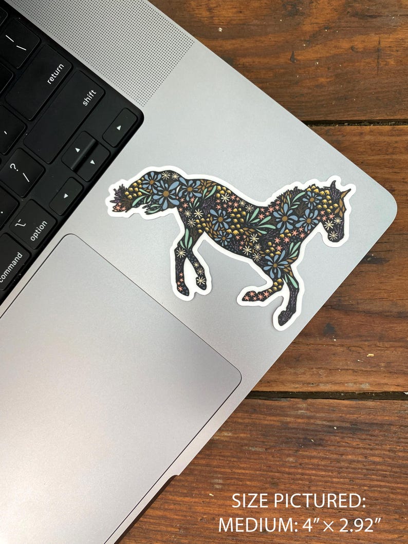 May include: A medium-sized sticker of a horse in a running pose, decorated with a floral pattern in shades of blue, yellow, and pink. The sticker is placed on a laptop. The size is 4" x 2.92".