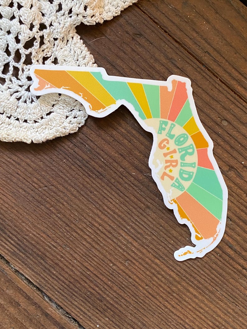 May include: A sticker of the state of Florida with a retro sunburst design and the text "Florida Girl" in a circle.