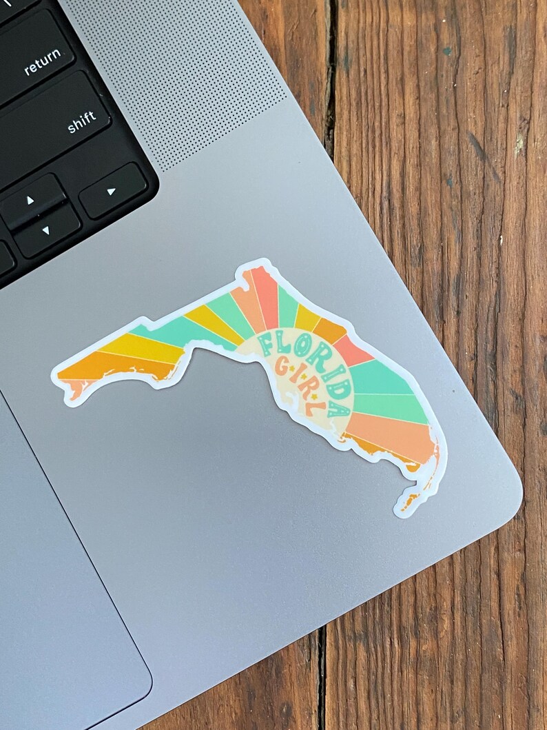 May include: A sticker of the state of Florida with a sunset design and the text "Florida Girl" in a retro font.