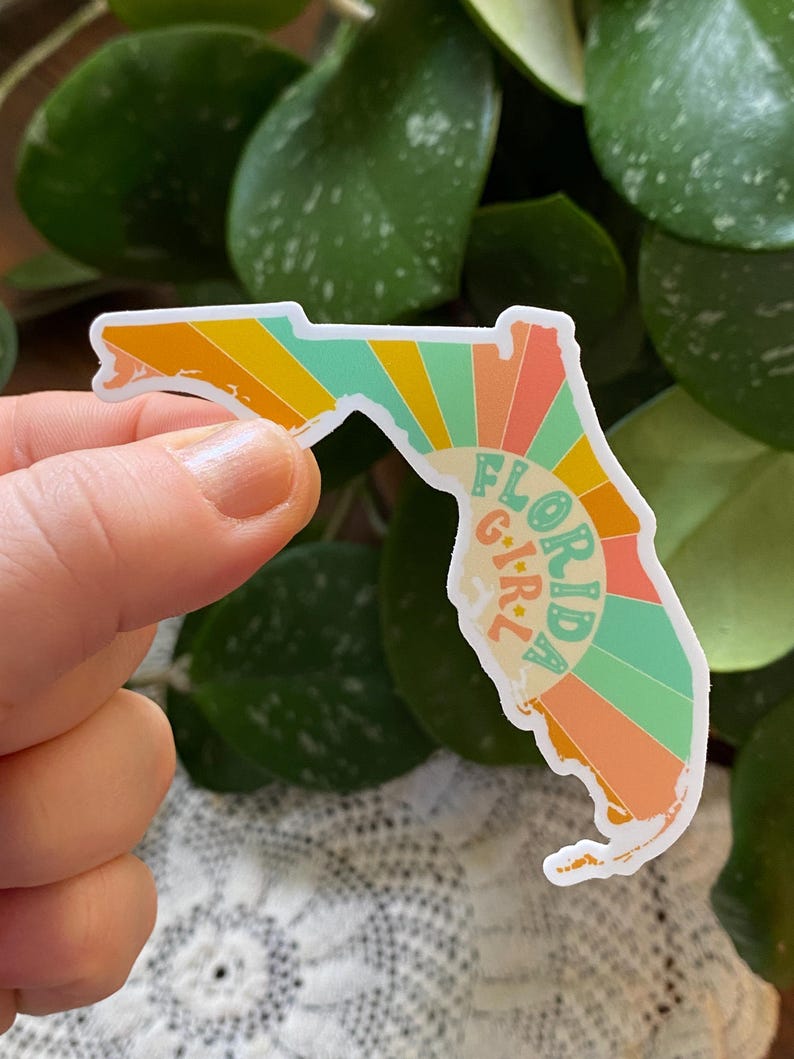 May include: A sticker of the state of Florida with a retro sunburst design and the text "Florida Girl" in a circle.