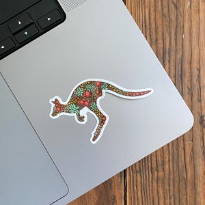 May include: A sticker of a kangaroo with a floral pattern in shades of brown, green, red, and white. The kangaroo is in a jumping pose.