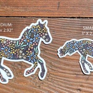 May include: Two horse stickers with floral patterns. The larger sticker is 4" x 2.92" and the smaller is 3" x 2.19". The horses are decorated with blue, yellow, and pink flowers on a dark background.