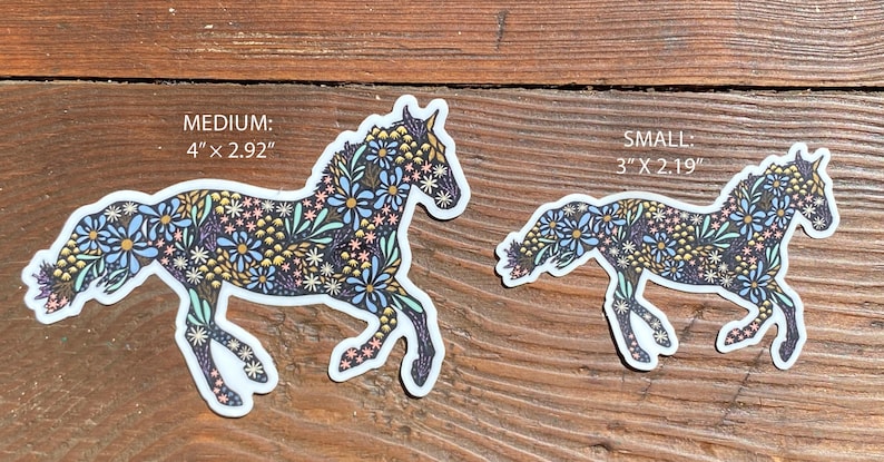May include: Two horse stickers with floral patterns. The larger sticker is 4" x 2.92" and the smaller is 3" x 2.19". The horses are decorated with blue, yellow, and pink flowers on a dark background.