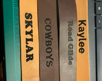 May include: Four leather wristbands in tan and brown hues, each with a snap fastener. The wristbands are engraved with the names "Skylar" and "Kaylee", and the words "Cowboys" and "Road Glide".