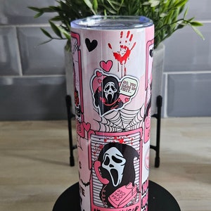 May include: Pink and black stainless steel tumbler with a graphic of a ghost wearing a mask and holding a phone. The text on the tumbler says "No you hang up first..." and "No you hang up".