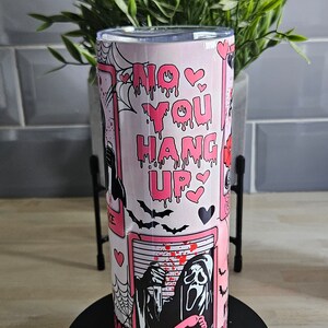 May include: Pink and black tumbler with a graphic of a ghost holding a phone and the text "No You Hang Up".