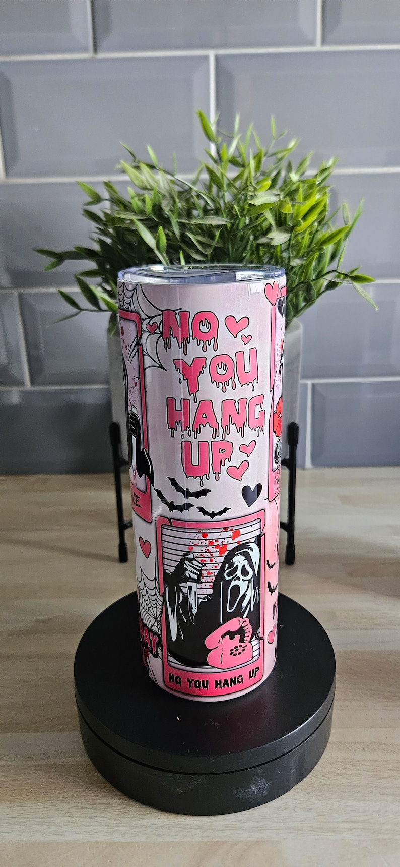 May include: Pink and black tumbler with a graphic of a ghost holding a phone and the text "No You Hang Up".